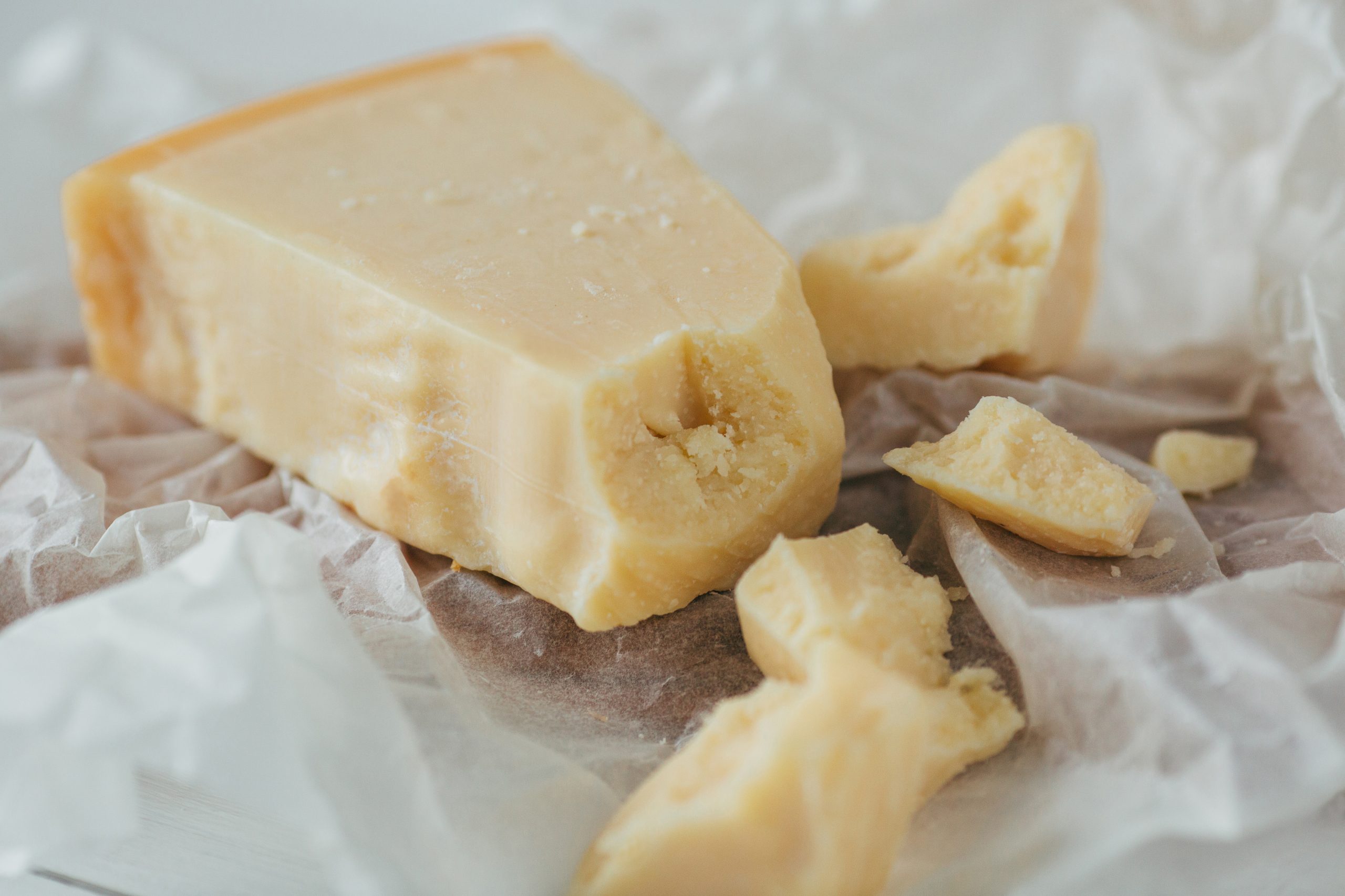 Parmesan cheese. Delicious italian parmesan cheese on white parchment. Pieces of Parmesan cheese